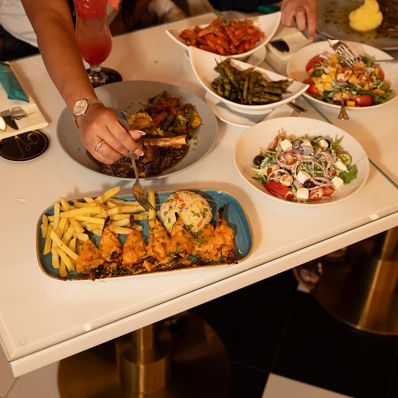 A woman using a fork to eat from one of the dishes on the table 
