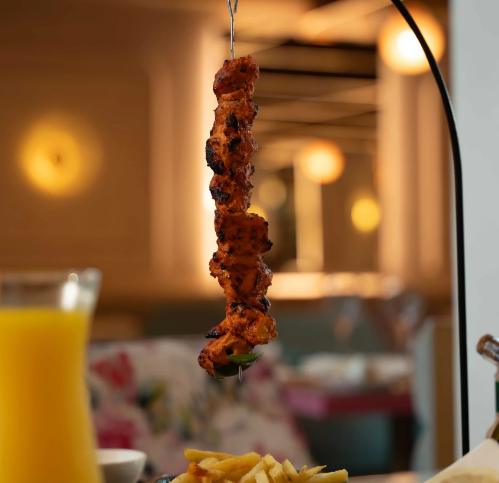 A skewer with grilled meat, along with a drink and fries