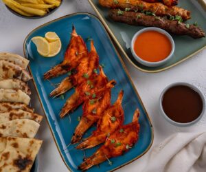 Flame-grilled Chooza Chicken served on a rustic table, paired with fries and sauces, showcasing a traditional South African meal at Villamoura Dubai.