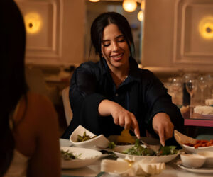 Woman serving African food in a restaurant, smiling and enjoying a meal.
